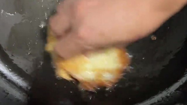 Man cooks stir-fry in a hot sizzling wok using only his bare hands