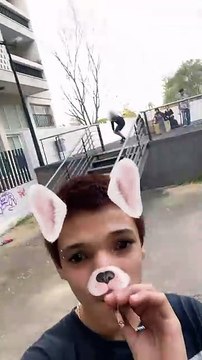 Skateboarder boardslides handrail then falls and land on rear while friend records using dog filter