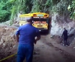 Conductor se arriesga al conducir un bus en una carretera destruida por lluvias