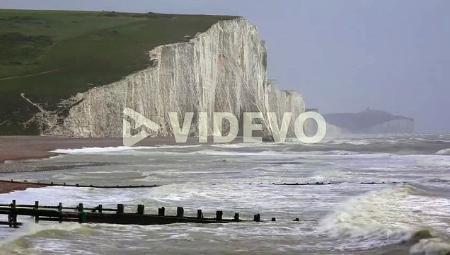 The sea breaks along wooden jetties along the shore of the White Cliffs of Dover at Beachy Head England 1