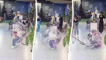 Frau fällt von hängendem Eierstuhl und wird darunter eingeklemmt