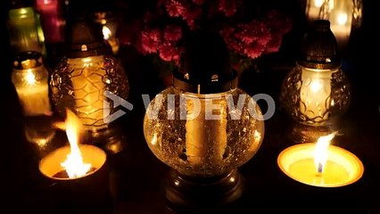 Grave candle lights burning at night on cemetery tomb