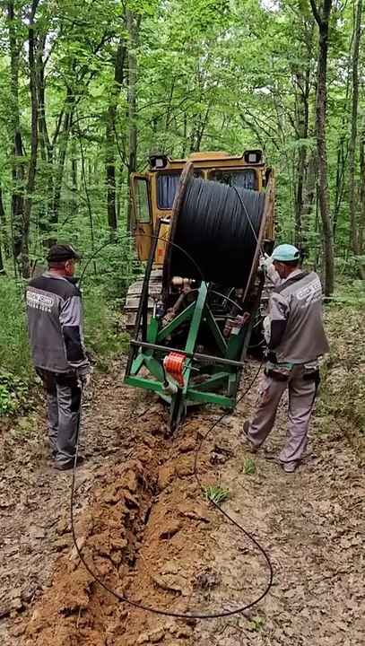 Trencher cable plow laying fiber through a forest