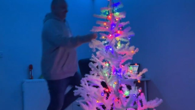Festive fun: Dad dances around the Christmas tree and shares laughter with his son