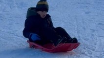 Tiny tot glides down a snow-covered slope on his sled like a pro