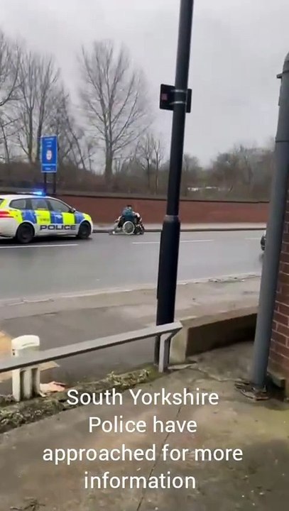 Police car chases mobility scooter along Meadowhall Road, Sheffield, with siren and blue lights
