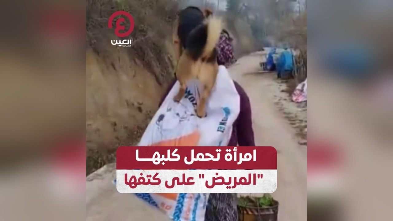 امرأة تحمل كلبها المريض على كتفها