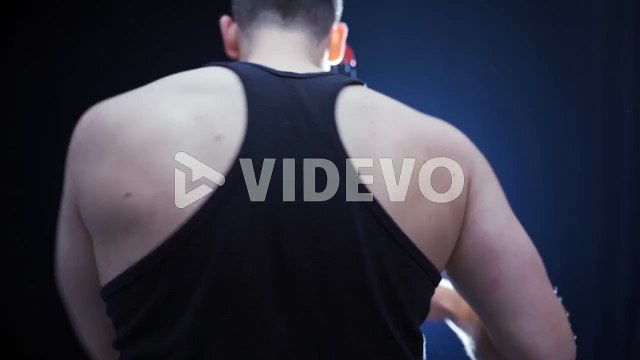 Aggressive strong male boxer punching a punching bag
