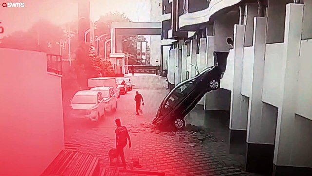 Auto stürzt aus Parkhaus im ersten Stock, nachdem der Fahrer versehentlich rückwärts durch die Wand gefahren ist