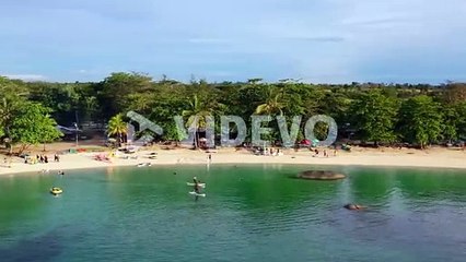 tourists paddle boarding on tropical beach at Tanjung