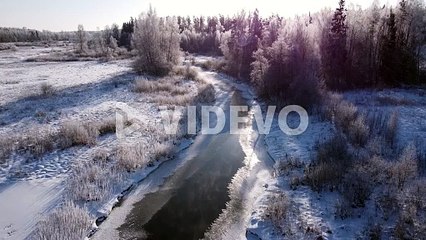 Winter partially frozen river in forest landscape aerial view