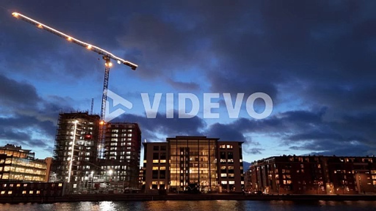 Illuminated crane and buildings at construction site on Malmo waterfront, drone