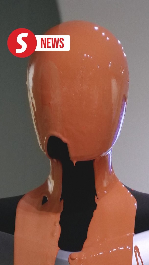 ⁣Activists pour orange liquid over robot at Elon Musk's Tesla store in London
