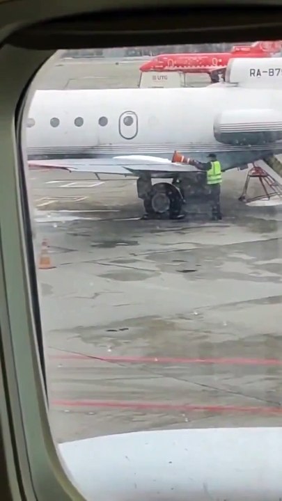 Cet employé d'aéroport utilise un cône pour déneiger une aile d'avion...