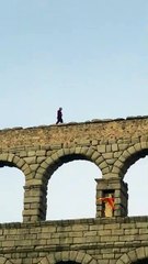 Un hombre camina por encima del acueducto de Segovia