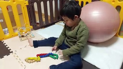 百玉そろばんの玩具の玉を繋いでつくった数珠のオモチャ遊びに精を出す4歳児男の子（発達障がい（知的障害）-自閉性スペクトラム症）