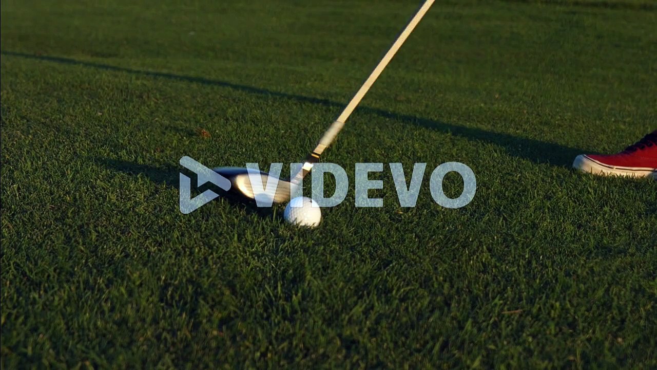 A golfer lining up a shot with a ball on a golf course