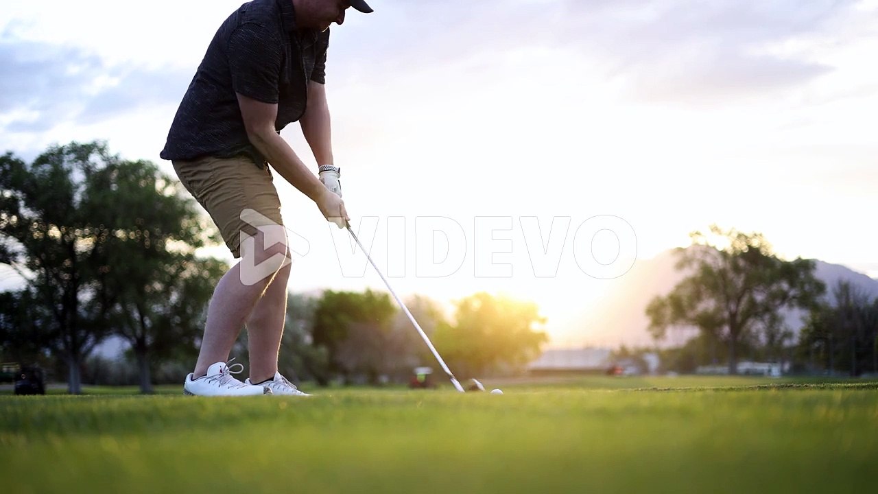 Golfer Swinging and Hitting Ball on Golf Course Fairway with Sun Flare