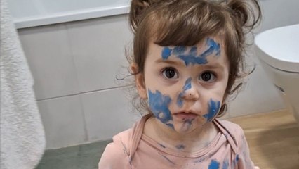 Little girl uses her brother’s watercolors to smear blue on her face and outfit