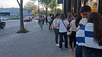 La gente se agolpa en los alrededores de un centro comercial para coger wifi