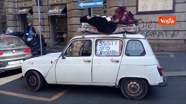 Shh, sto lavorando , un uomo dorme su tetto macchina a Milano durante corteo del Primo Maggio
