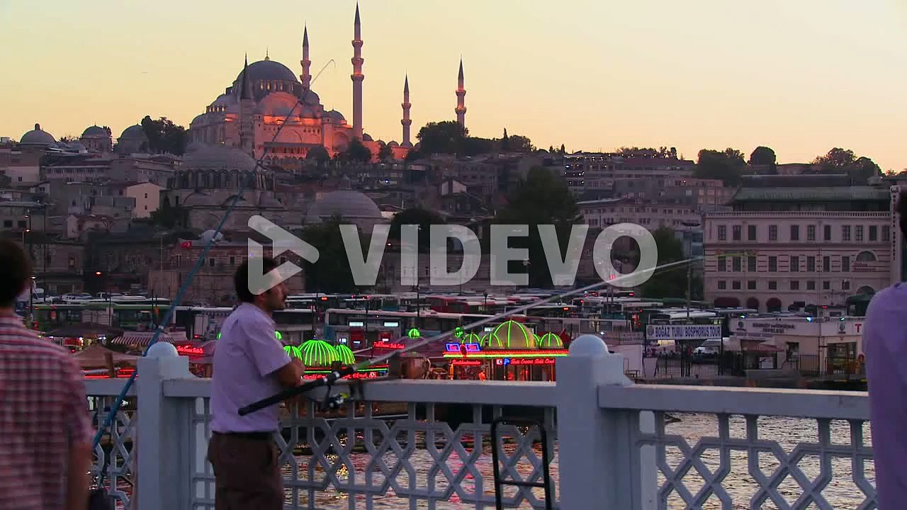 Fisherman and colorful boats at dusk in front of a mosque in Istanbul Turkey