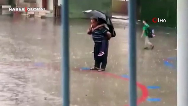 Dede torununu sırtına alarak yağmur altında İstiklal Marşı okudu