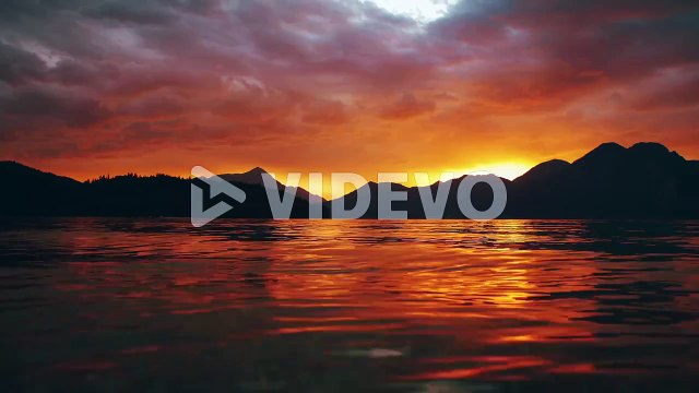 Scenic cinemagraph - seamless video loop of a beautiful and romantic sunset at mountain lake Walchensee in Southern Germany - Bavaria with moving red evening clouds and calm waves in real time