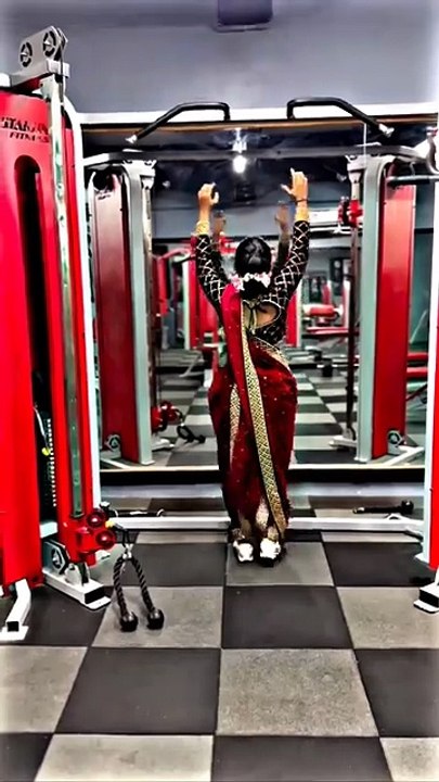 A South Asian girl in a sari is working out in the gym.