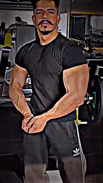 A Desi boy shows off his arm muscles in the gym after his workout.
