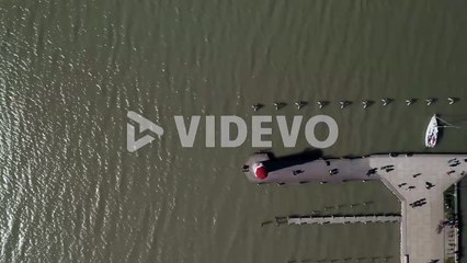 Aerial birds eye view dolly shot of an old lighthouse with a pier