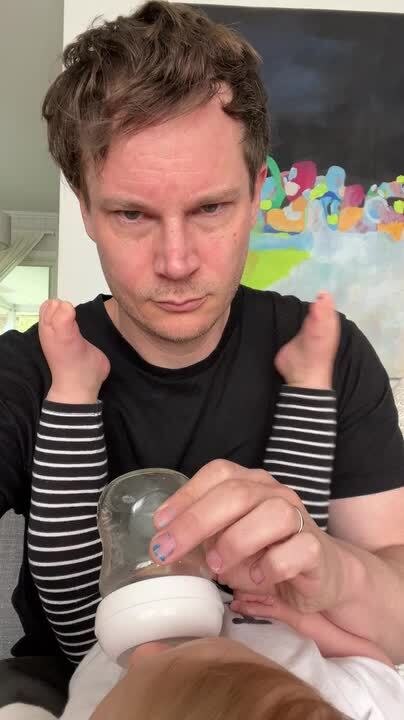 Baby Playfully Kicks Father While Drinking Milk From Bottle