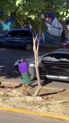 A woman is hitting cars with glass bottles.