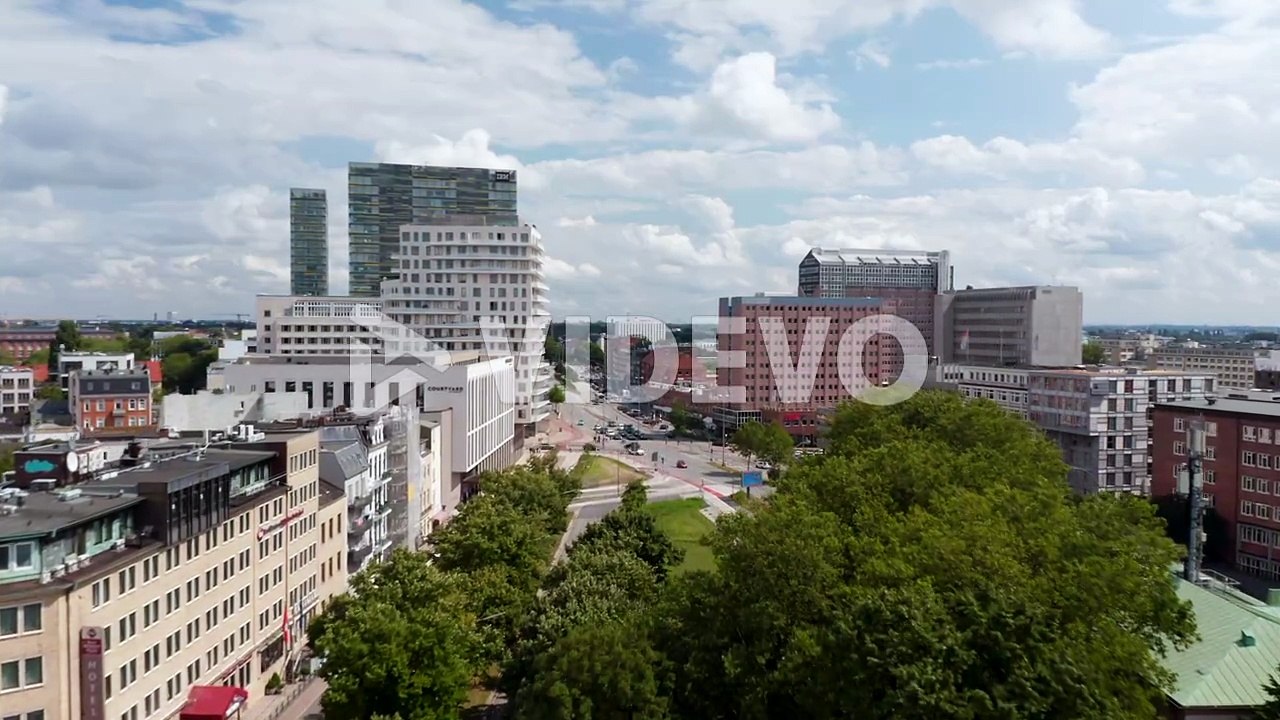 Forwards fly above wide street in urban neighbourhood with various buildings