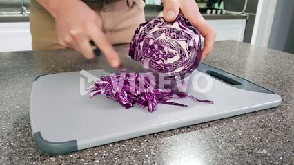 Closeup of a man slicing red cabbage in a kitchen home