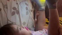 Baby girl balances tablet on her feet and watches show with focus
