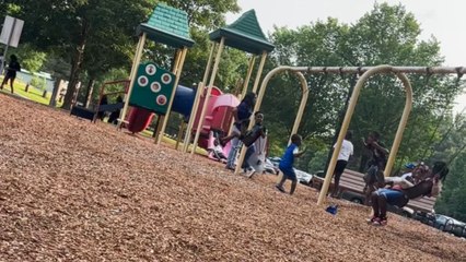 Two kids fall back-to-back while playing on the swings at the playground