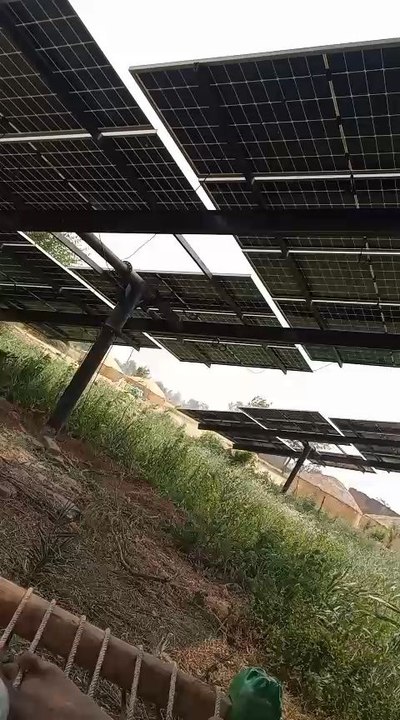 solar panel installation on our tubewell system. Two sturdy poles were self-installed to support the panels, and the setup is shown enduring strong wind conditions.  real rural environment.  self-reliance and clean energy utilization in farming areas.