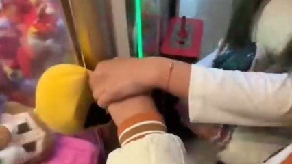 Claw machine's glass breaks as two mischievous souls attempt to retrieve toy by hand