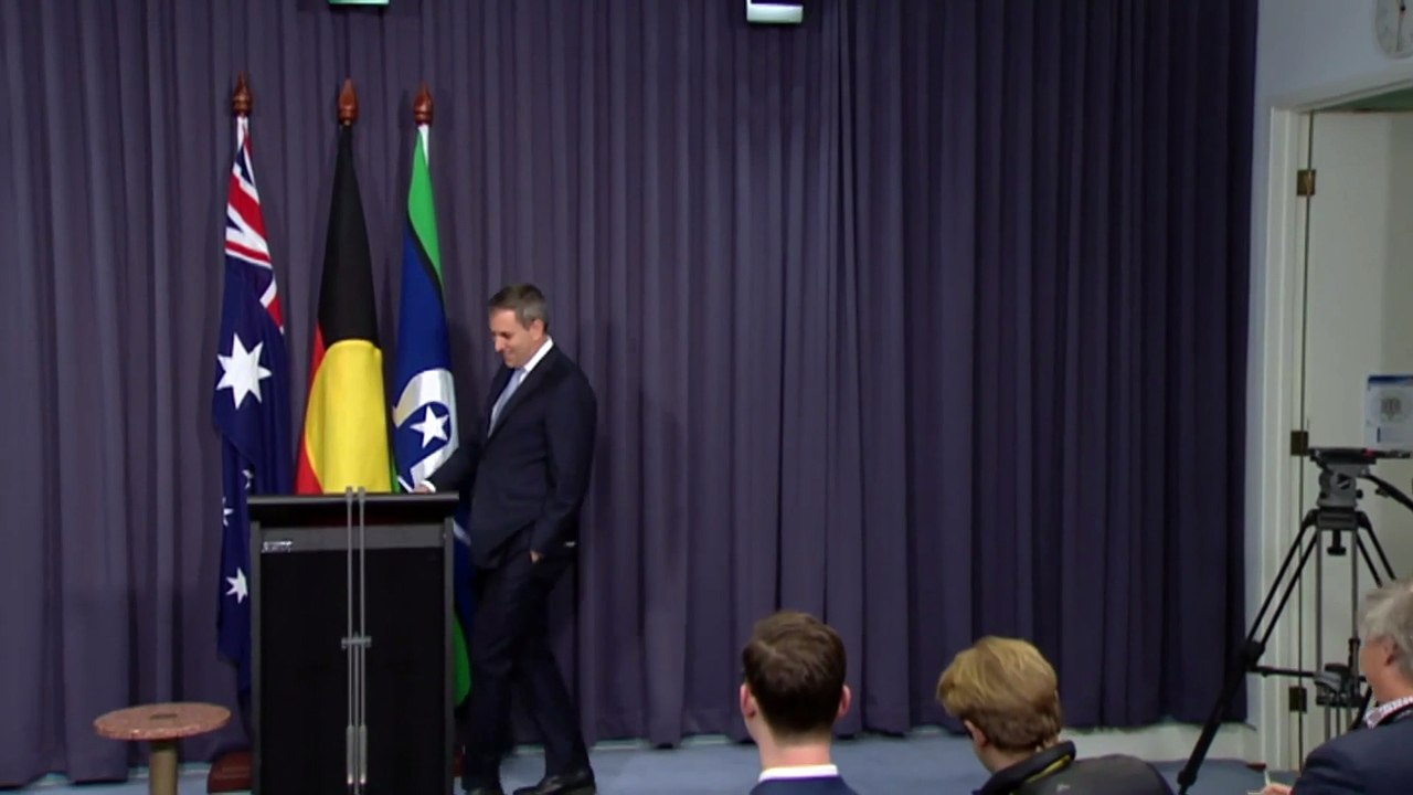 Jim Chalmers walks to presser podium; images of Treasury brief