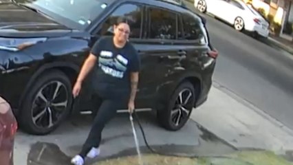 Sprinkler shoots up as woman pulls water hose to untangle garden mess