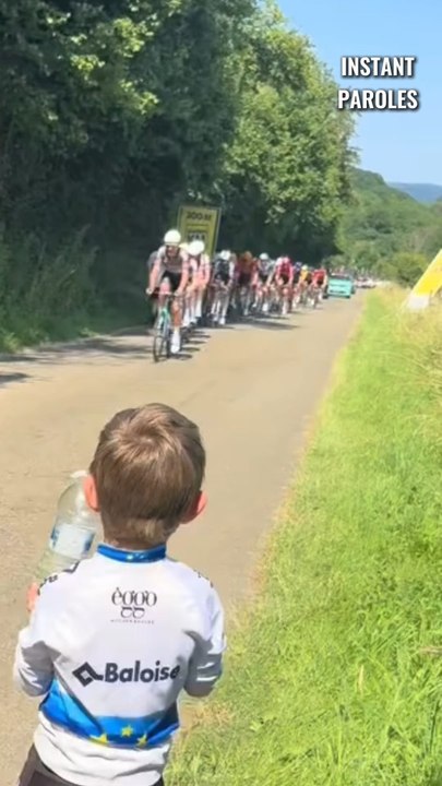 Ce petit garçon tend une bouteille d’eau aux cyclistes lors de cette course