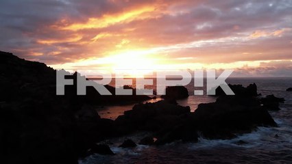 rocks and waving sea against sundown sky