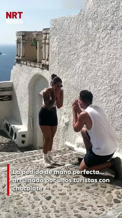 💍 Él planeó la pedida perfecta en Santorini, el lugar ideal, el momento soñado… Pero dos turistas decidieron colarse comiendo chocolate y se robaron el show 🤦‍♂️🍫 “Los tres primeros segundos fueron mágicos”, lamentó el novio.