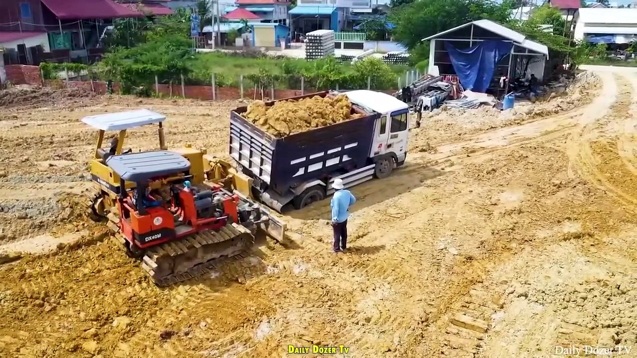 Bulldozer Komatsu D31P Pushing Soil and Stone Fill the Hole with A lot of Dump truck Unloading Soil