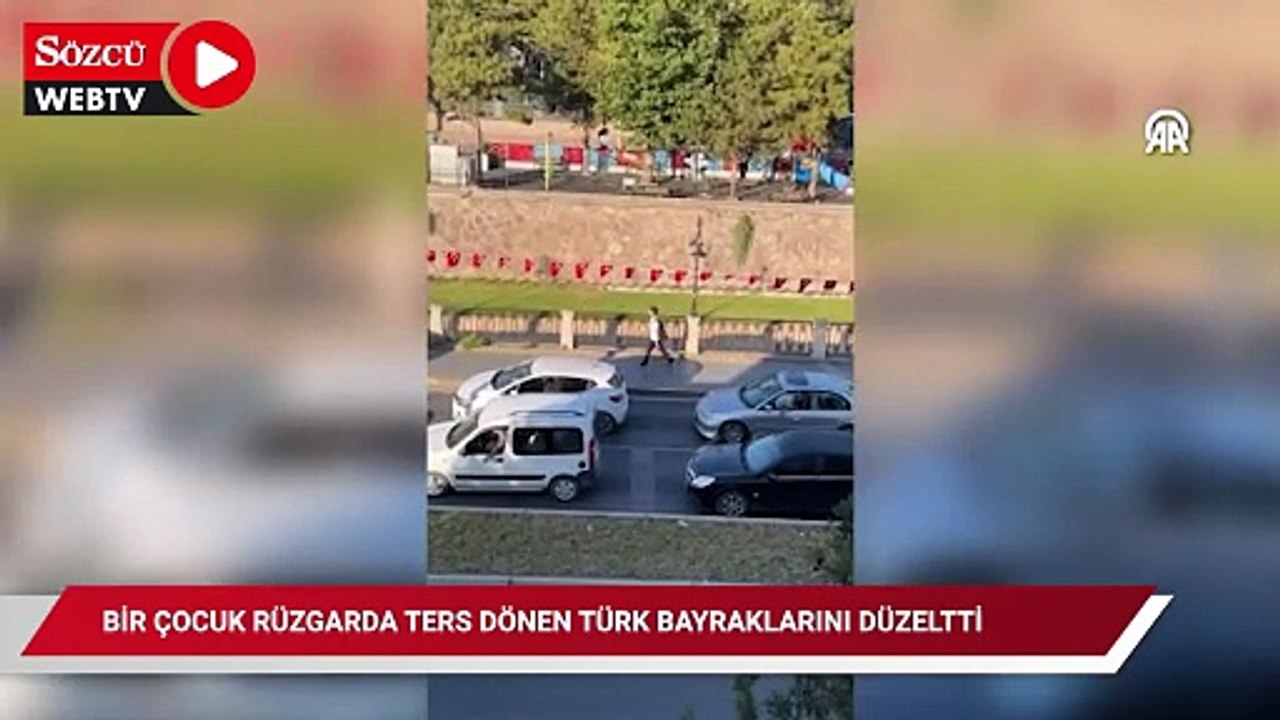 Bir çocuk rüzgarda ters dönen Türk bayraklarını düzeltti