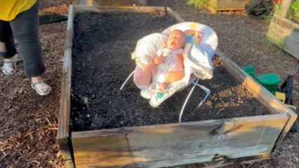 Baby girl gets splashed by accident as mom focuses on plants