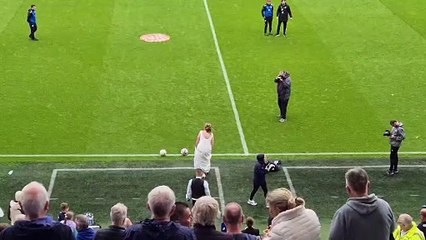 Bride and groom kick football at pizza on pitch