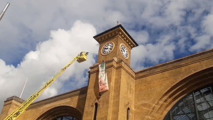 A  man and his pet dog have climbed Kings Cross station with a Freedom for Iran flag