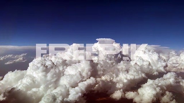 stunning pilot view from a jet cockpit avoiding stormy cumulus clouds in a messy and deep blue sky